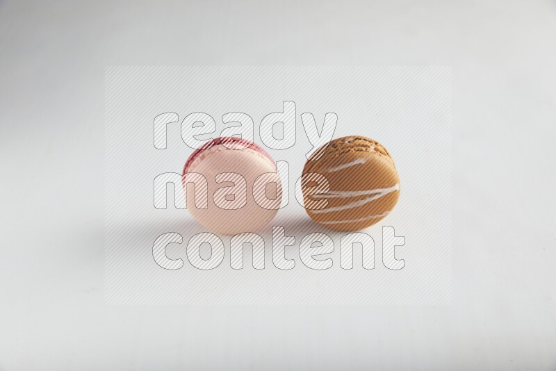 45º Shot of of two assorted Brown Irish Cream, and Pink Litchi Raspberry macarons on white background