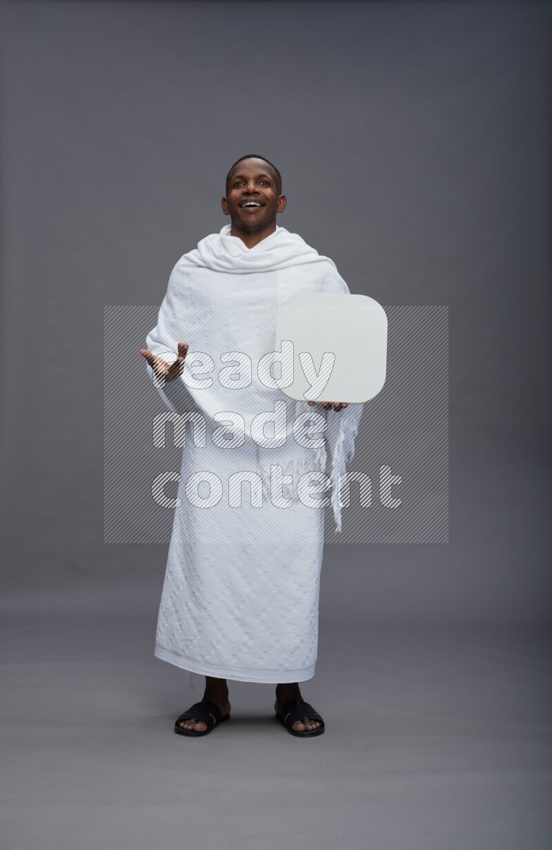 A man wearing Ehram Standing holding social media sign on gray background