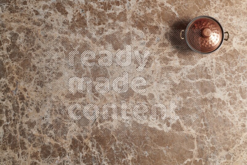 A small copper pot on beige marble background