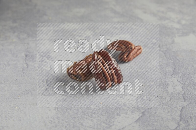 TWO pecan stuffed dates on alight grey background