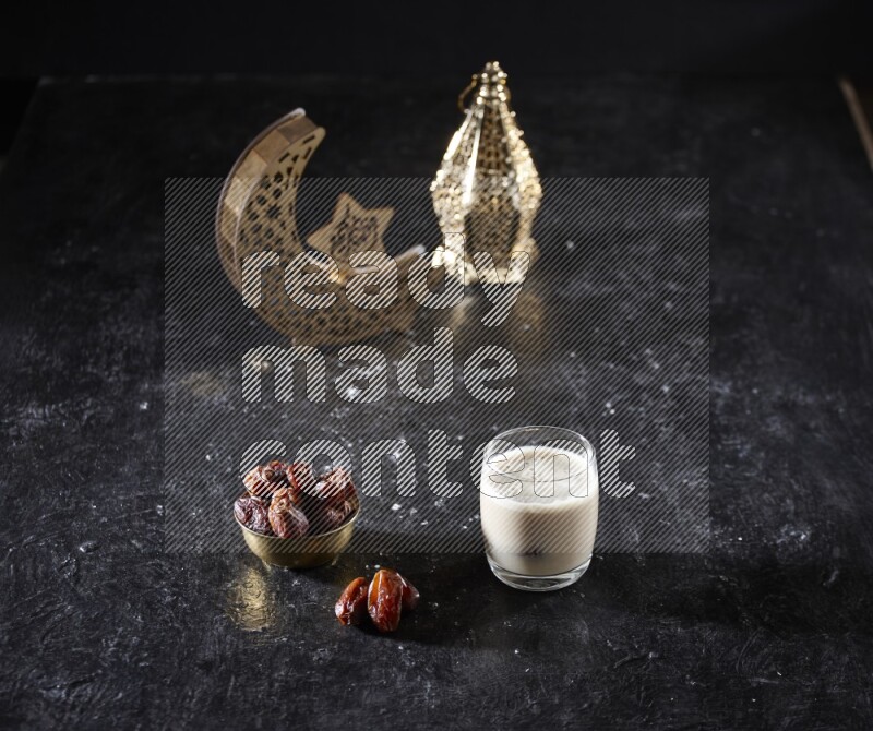 Dates in a metal bowl with dates smoothie beside golden lanterns in a dark setup