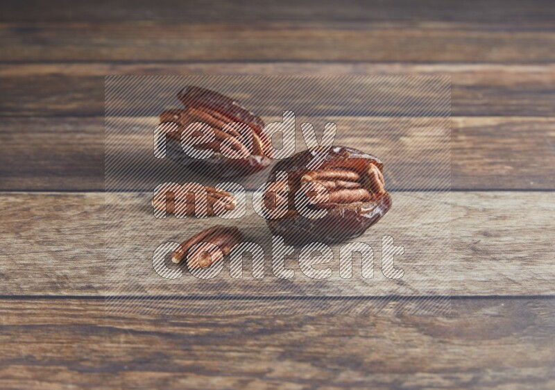 two pecan stuffed madjoul date on a wooden background