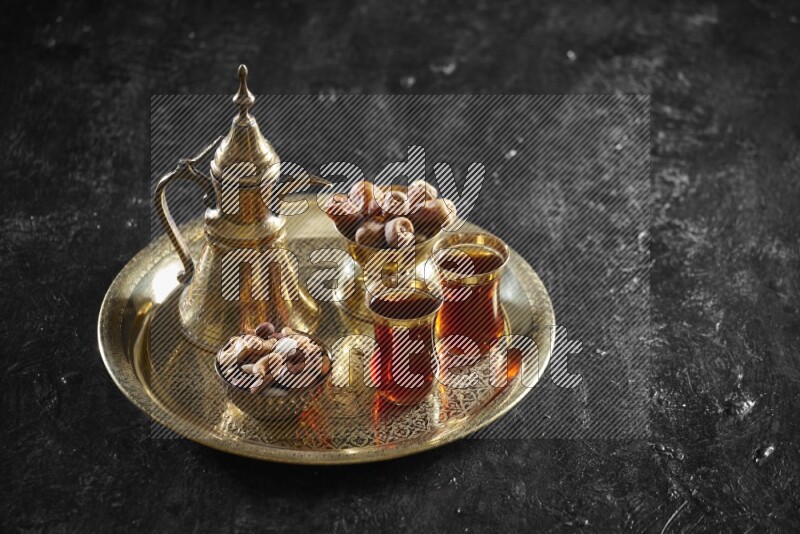 Nuts with dates and a drink on a metal tray in a dark setup