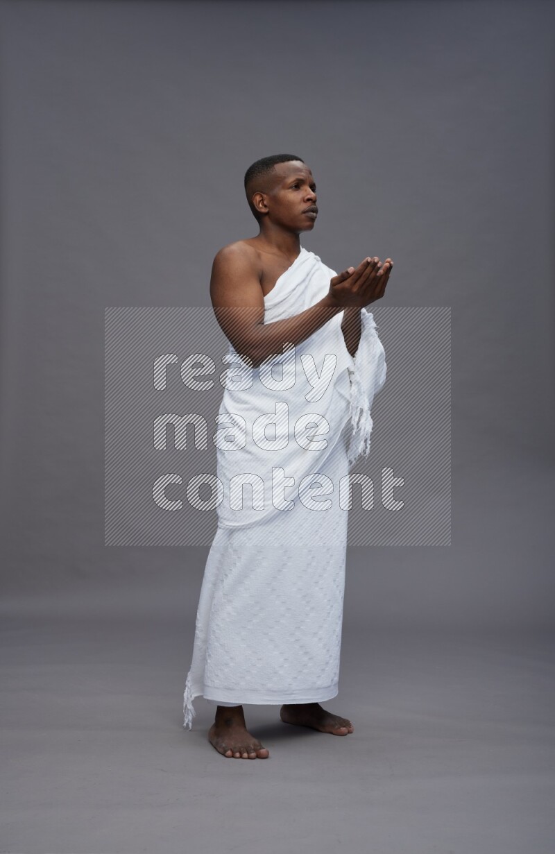 A man wearing Ehram Standing dua'a on gray background