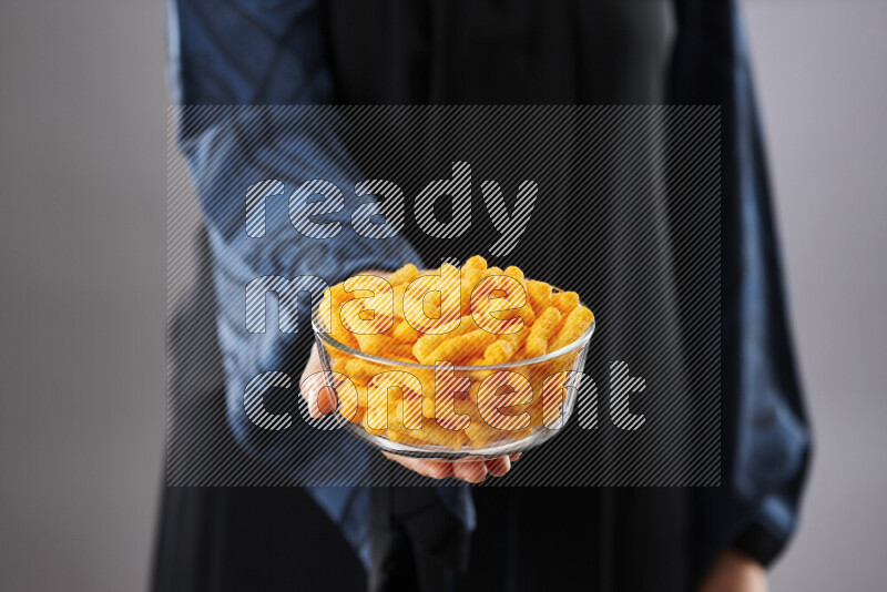 Woman in abaya holding different kinds of snacks in different positions