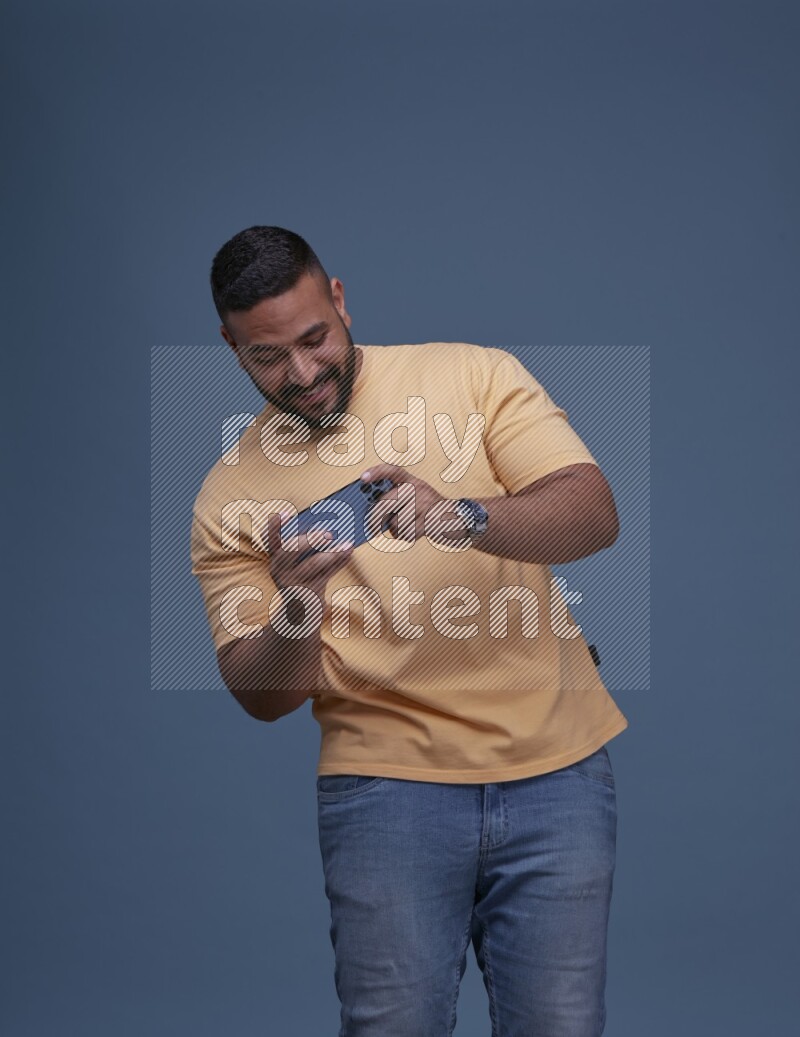 A man Playing Games on Smartphone on Blue Background wearing Orange T-shirt