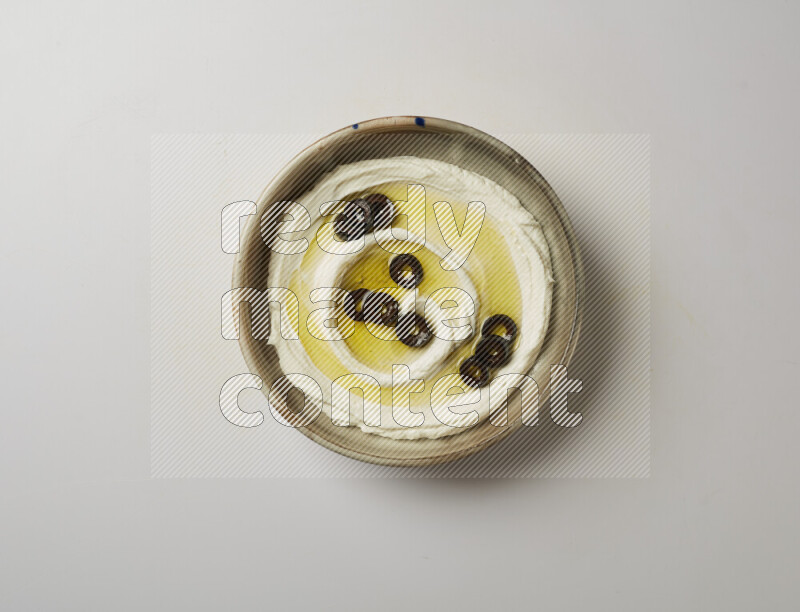 Lebnah garnished with sliced olives in a grey pottery plate on a white background