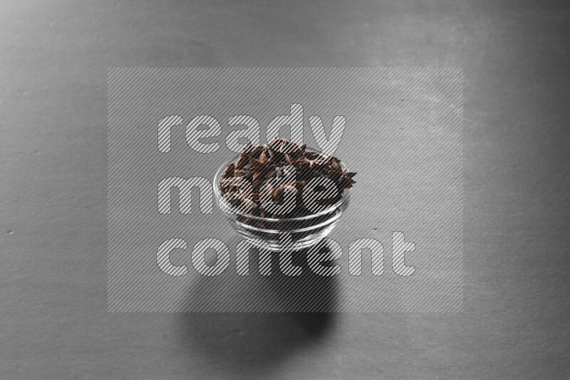 A glass bowl full of star anise on black flooring