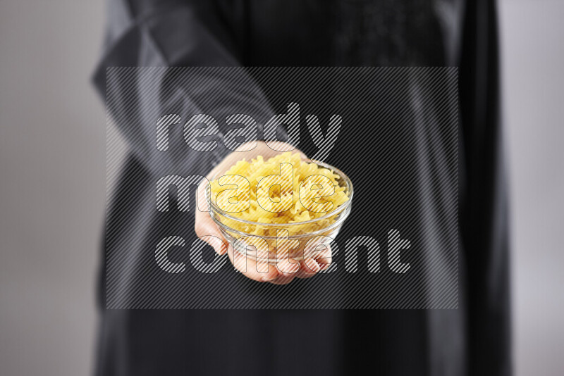 Woman in abaya holding different kinds of pasta in different positions