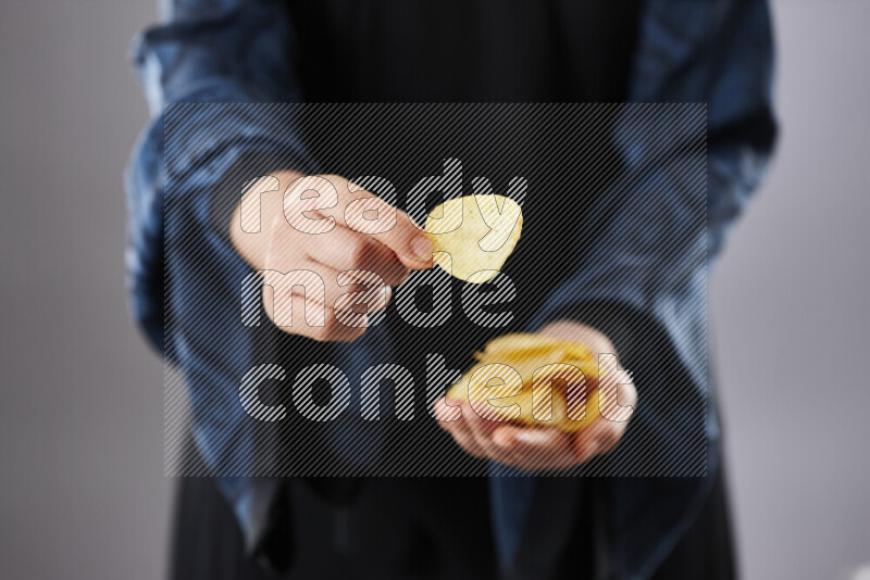Woman in abaya holding different kinds of snacks in different positions