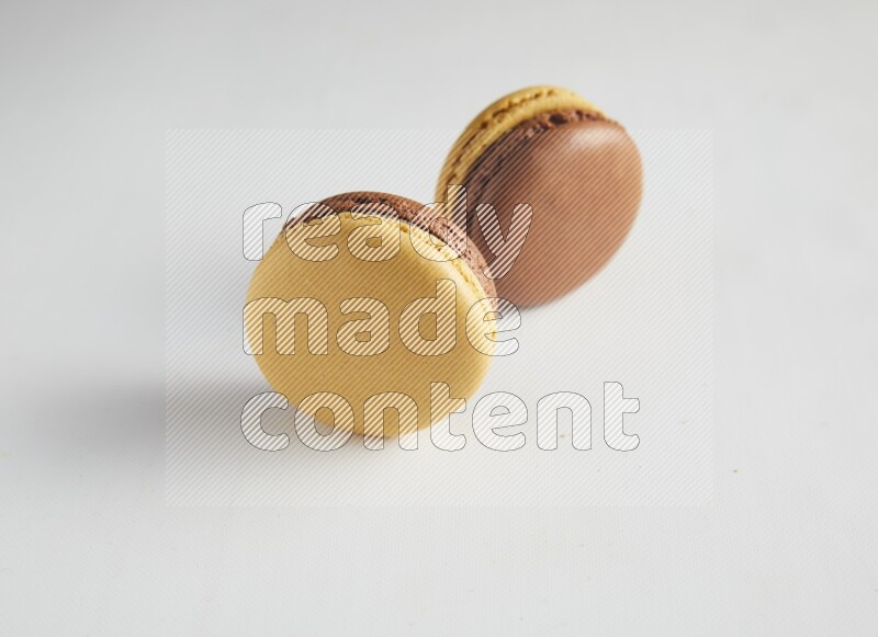 45º Shot of two Yellow and Brown Chai Latte macarons on white background