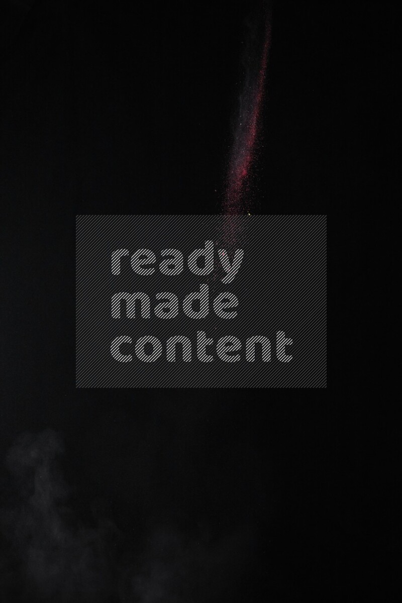 A side view of red powder explosion on black background