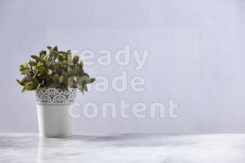 Green artificial plant in white decorative pot on grey marble background