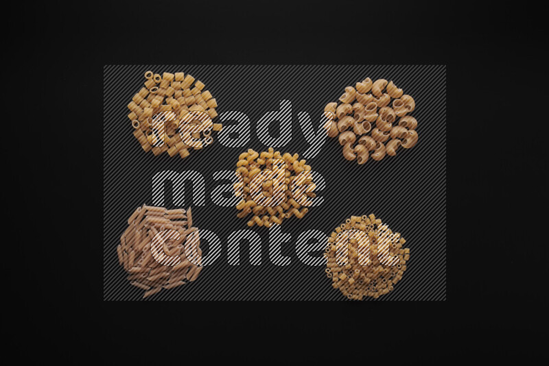 Different pasta types in bunches on black background