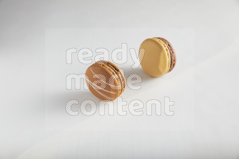 45º Shot of of two assorted Brown Irish Cream, and Yellow, and Brown Chai Latte macarons on white background
