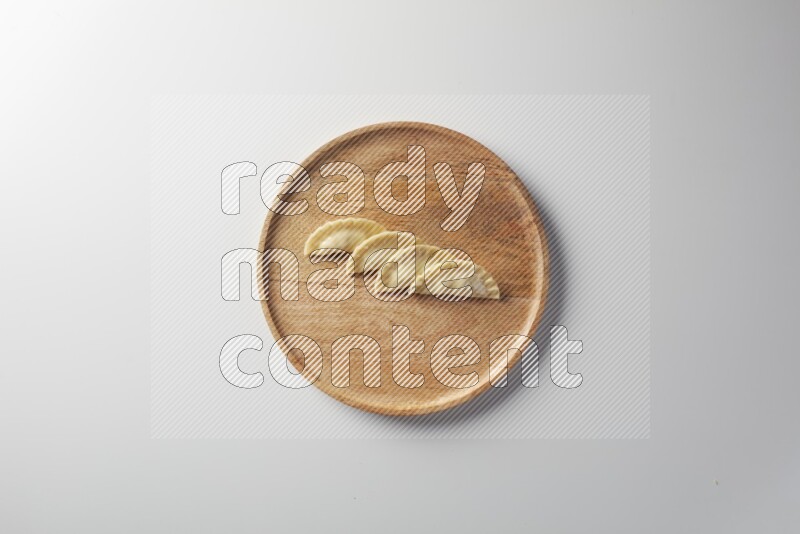 Four Sambosas on a wooden round plate on a white background