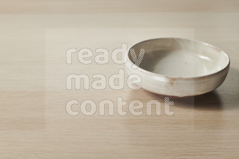 A beige pottery bowl on light wooden background