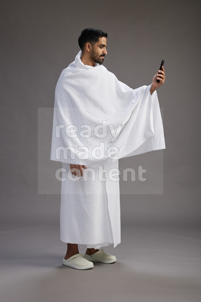 A man wearing Ehram Standing taking selfie on gray background