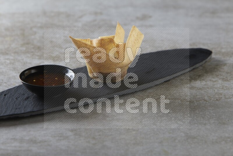 wonton cups with soy sauce ramkin on oval slate on grey textured counter top