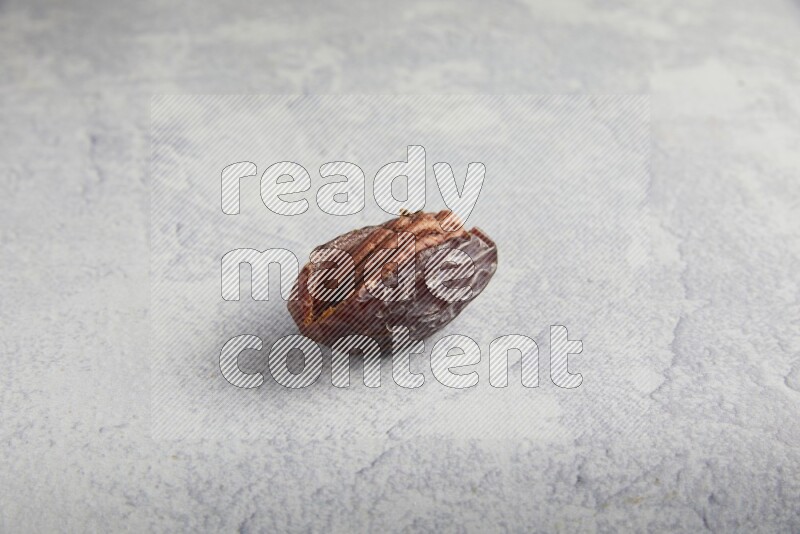 pecan stuffed madjoul date on a light grey background