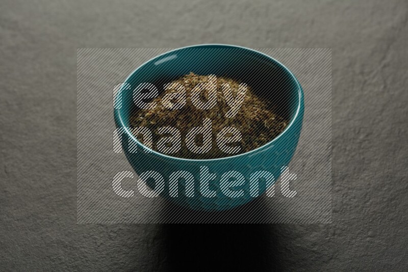 turquoise pottery round sauce bowl filled with herbs on grey textured countertop