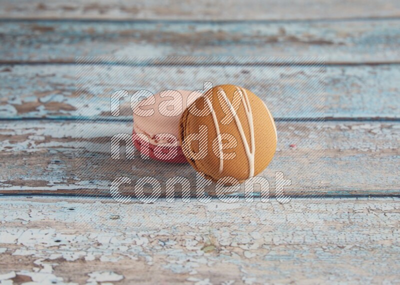 45º Shot of of two assorted Brown Irish Cream, and Pink Litchi Raspberry macarons on light blue background