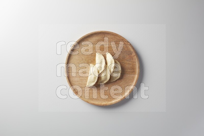 Five Sambosas on a wooden round plate on a white background