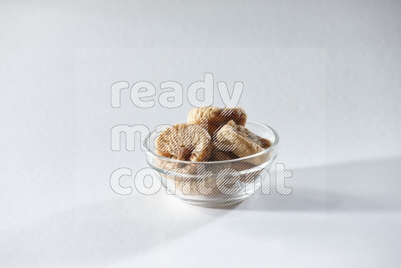 A glass bowl full of dried figs on a white background in different angles