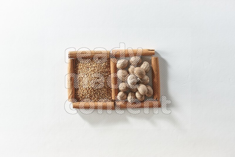مربعان من أعواد القرفة ممتلئان بحبوب الخردل وجوزة الطيب علي خلفية بيضاء