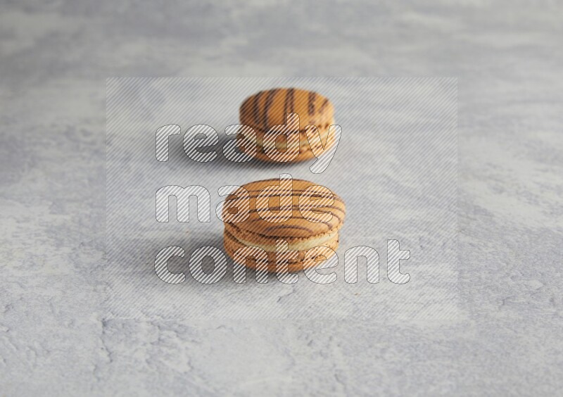 45º Shot of two light brown  Almond Cream macarons  on white  marble background