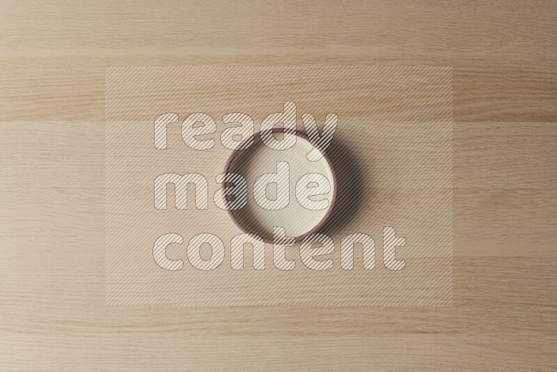 A beige pottery oven bowl on light wooden background
