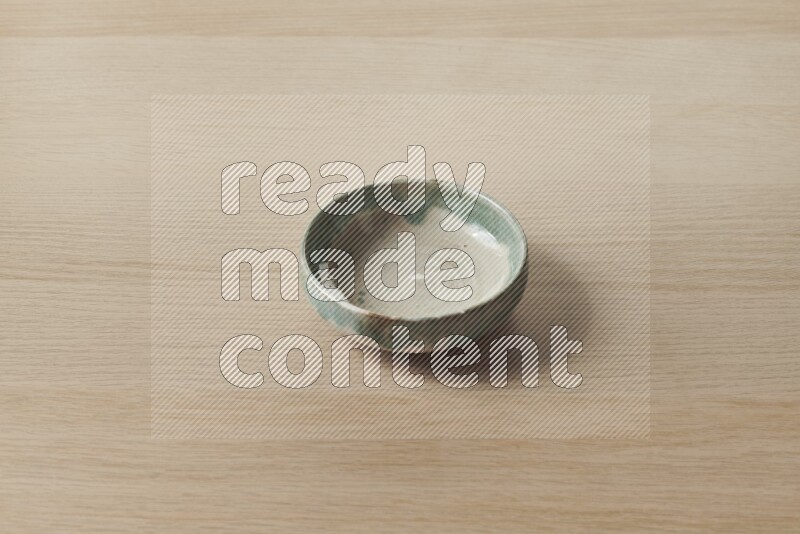 A multicolored pottery bowl on light wooden background