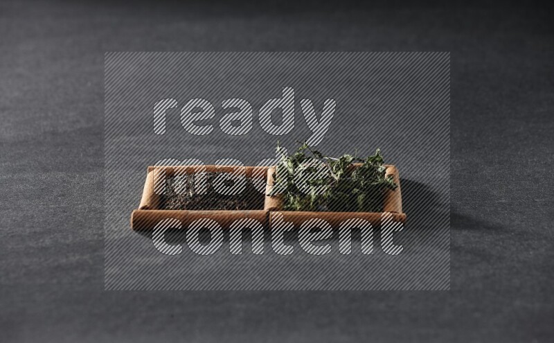 مربعان من أعواد القرفة ممتلئان بالشاي والنعناع المجفف علي خلفية سوداء