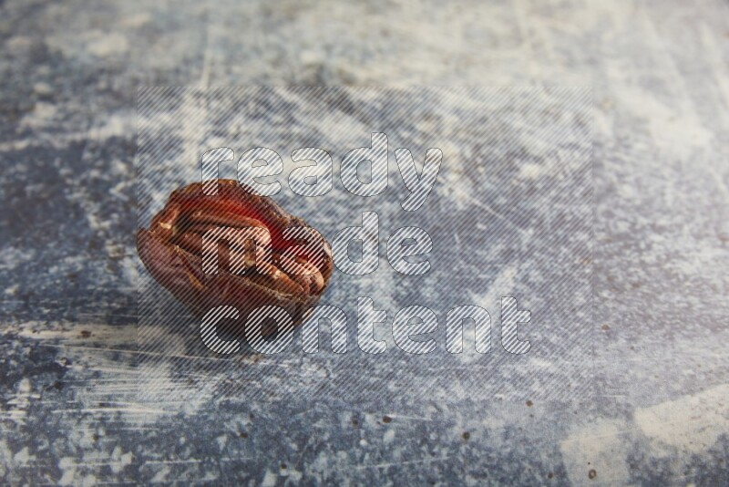pecan stuffed madjoul date on a rustic blue background