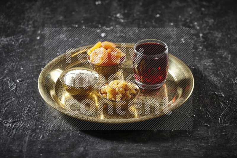Dried fruits in metal bowls with Hibiscus on a tray in dark setup