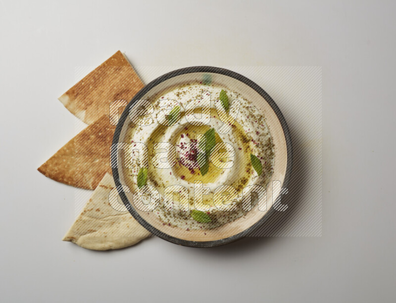 Lebnah garnished with zaater, mint & sumak in a pottery plate on a white background