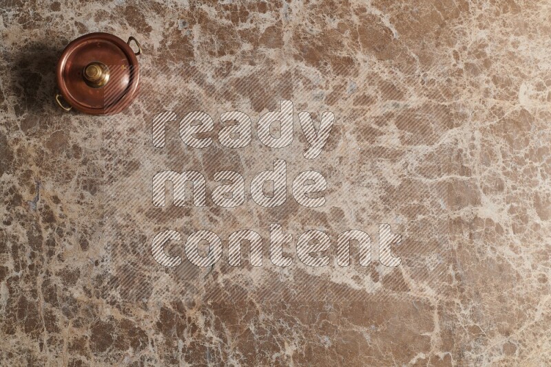 A small copper pot on beige marble background