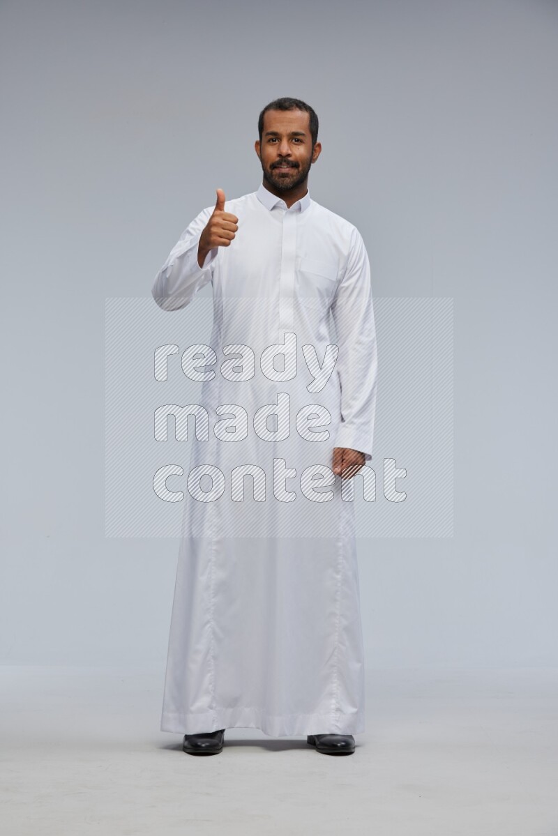 Saudi man Wearing Thob standing interacting with the camera on Gray background