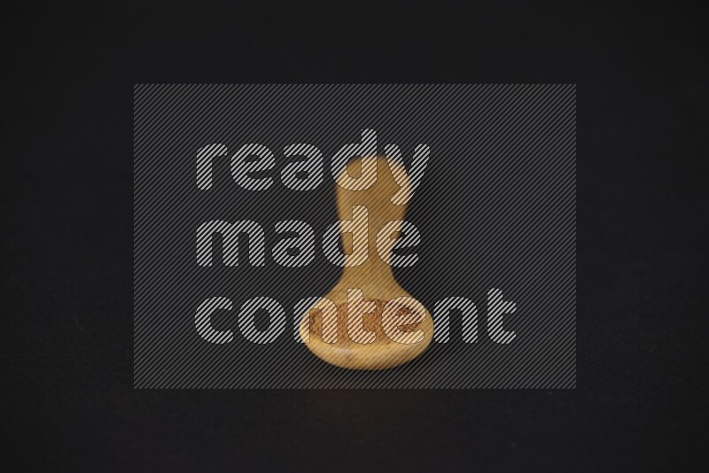 Cinnamon powder in a wooden spoon on a black background