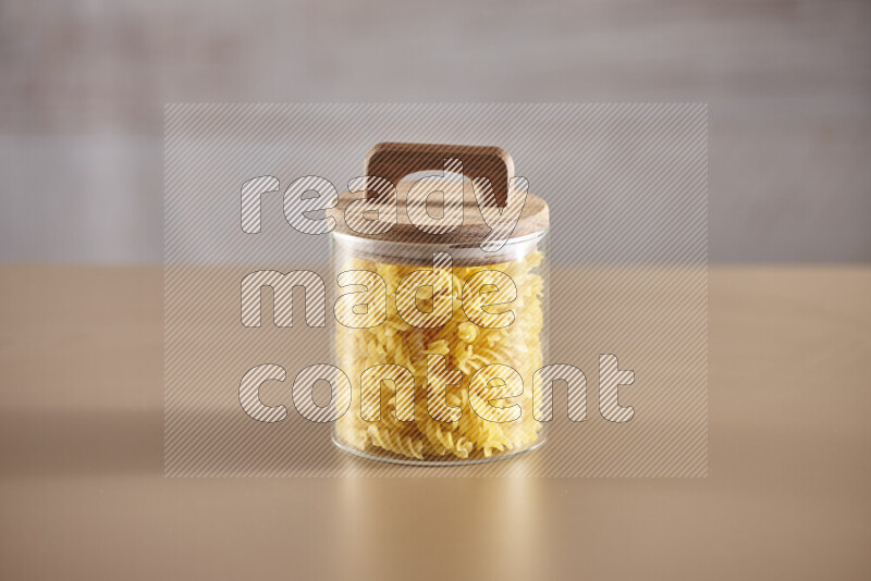 Raw pasta in glass jars on beige background