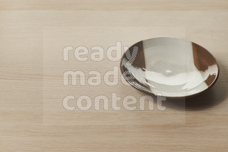 A multicolored pottery plate on light wooden background