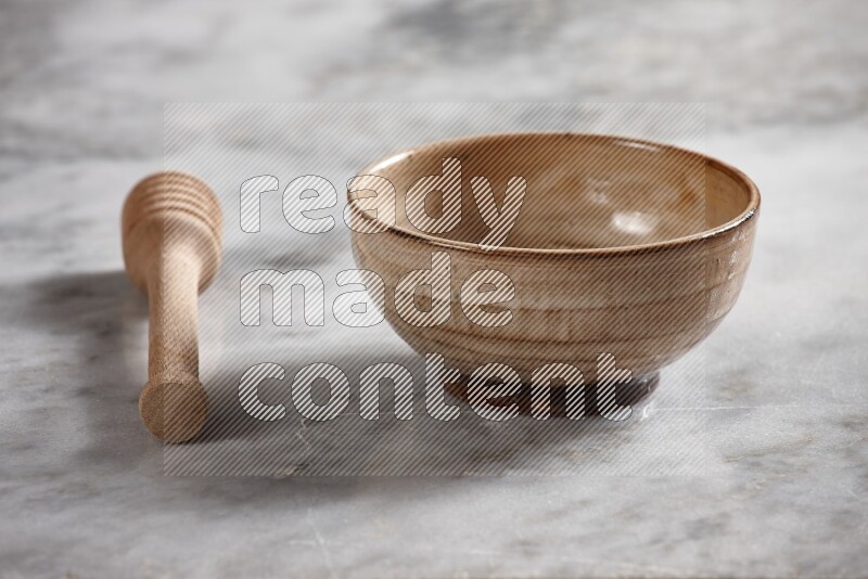 Beige pottery bowl with wooden honey dipper on the side on grey marble background