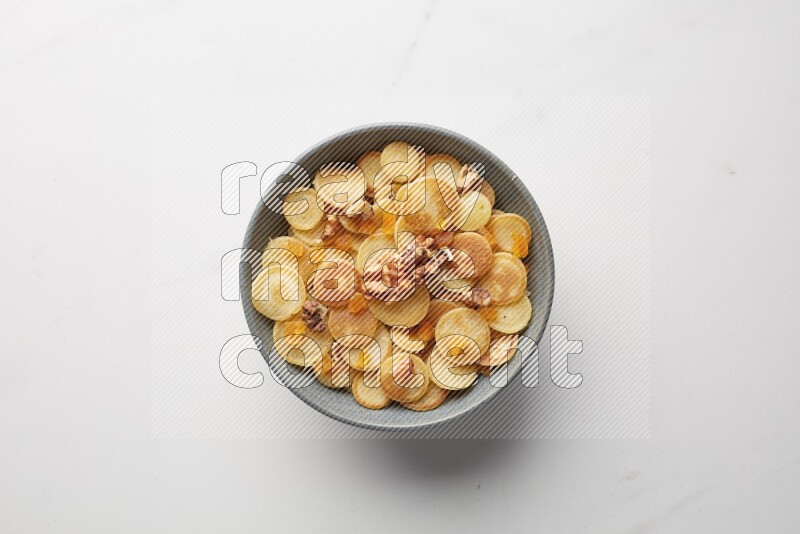 Top-view shot of walnut and apricot cereal pancakes in a round bowl on white background