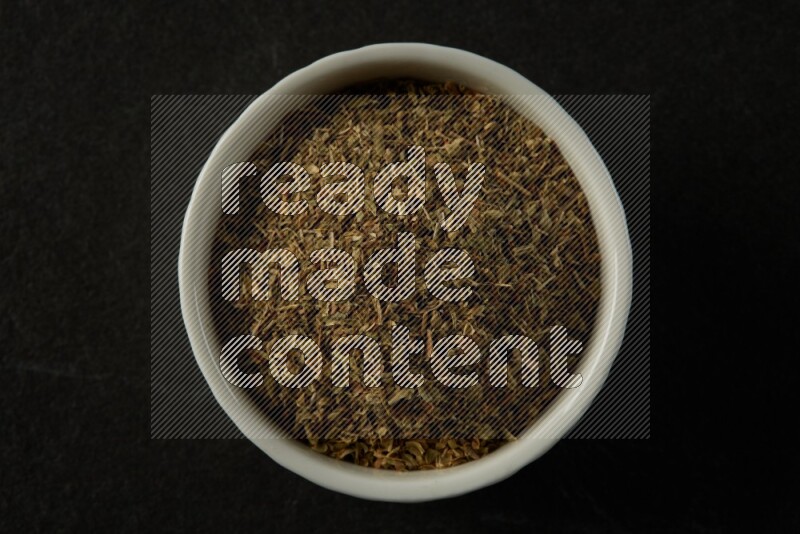 wooden round sauce bowl filled with herbs on grey textured countertop