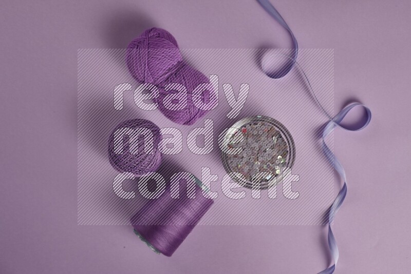 A purple collection of sewing and tailoring tools arranged on a purple background