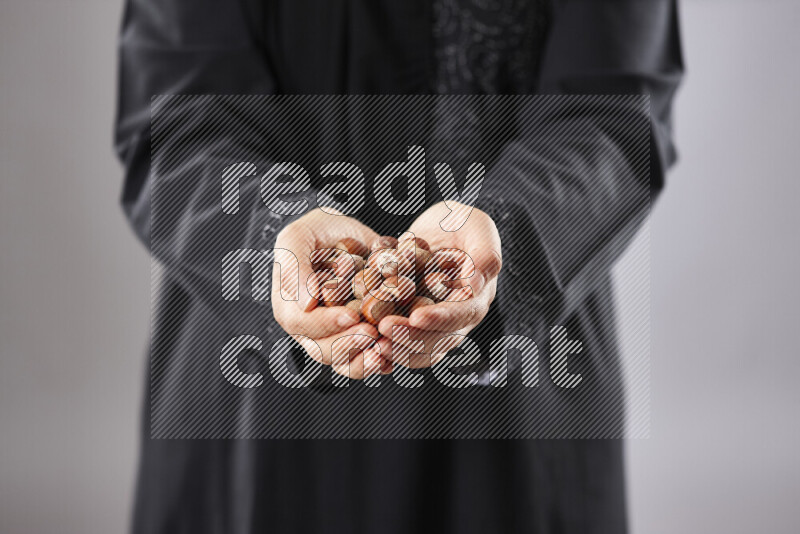 Woman in abaya holding different kinds of nuts in different positions