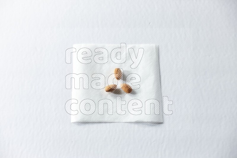 3 peeled almonds on a piece of paper on a white background in different angles