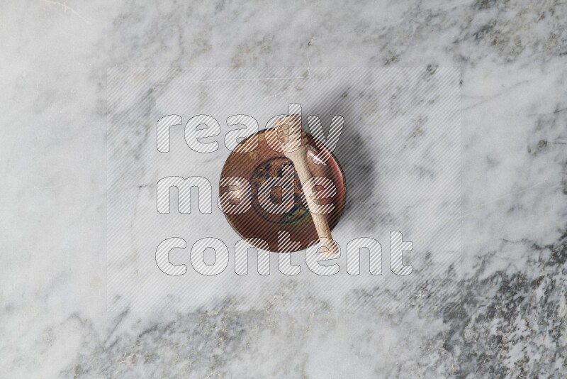 Decorative pottery plate with wooden honey dipper in it on grey marble background