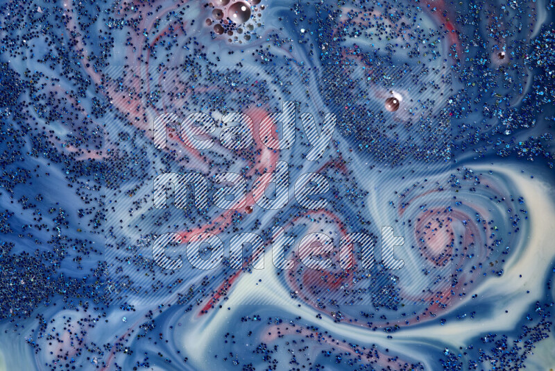 A close-up of sparkling blue glitter scattered on swirling blue and red background