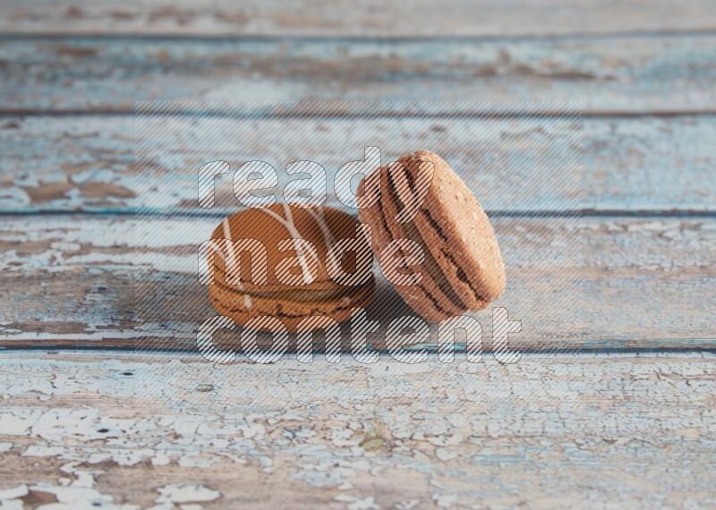 45º Shot of of two assorted Brown Irish Cream, and Brown Hazelnuts macarons  on light blue background